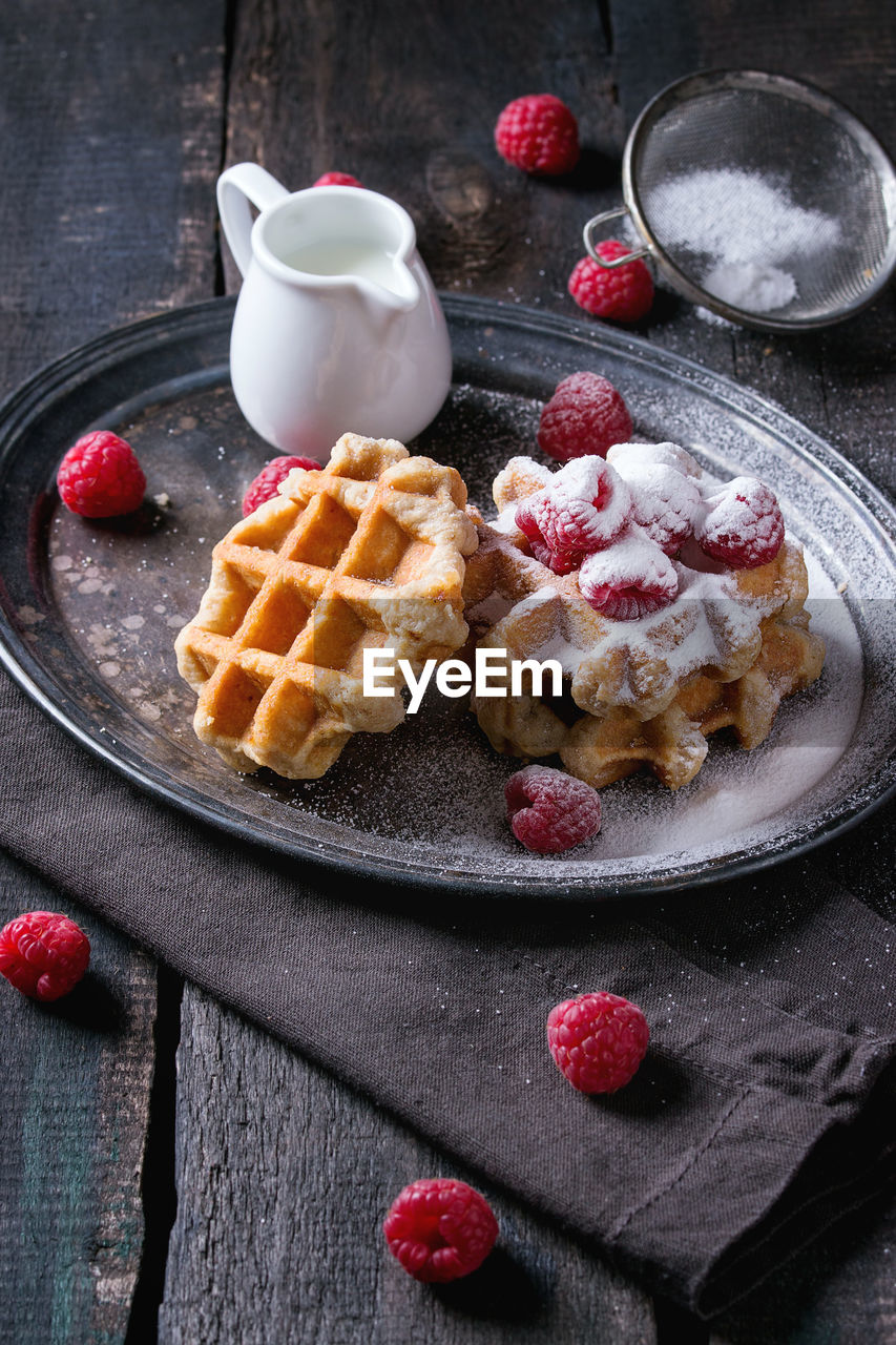 Close-up of waffles with raspberries in plate on table