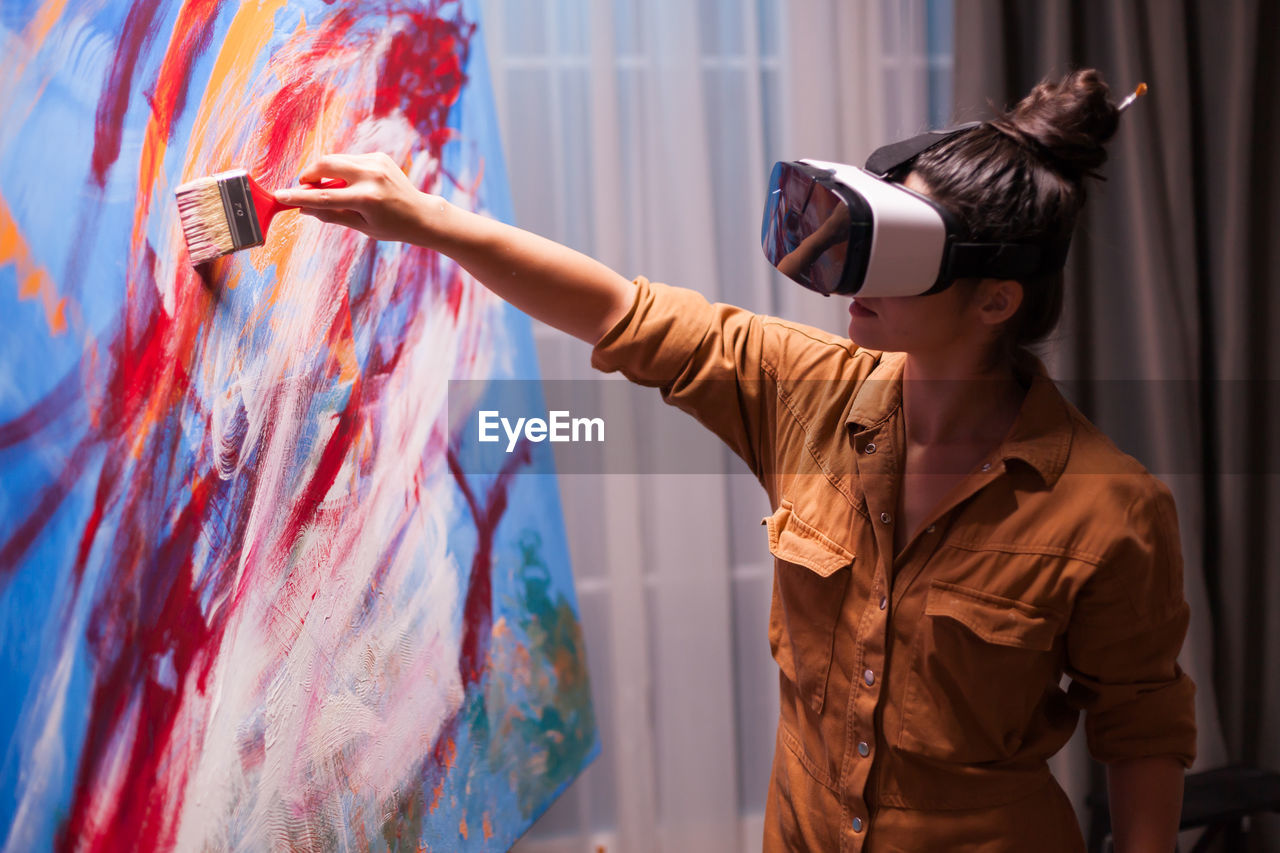Woman painting while wearing virtual reality headset