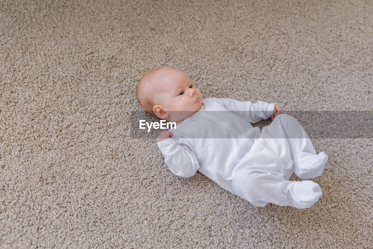 HIGH ANGLE VIEW OF CUTE BABY SLEEPING ON CARPET