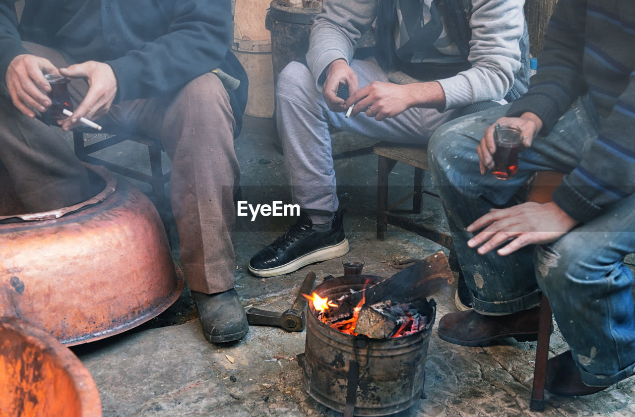 Low section of people sitting on floor in front of fire 