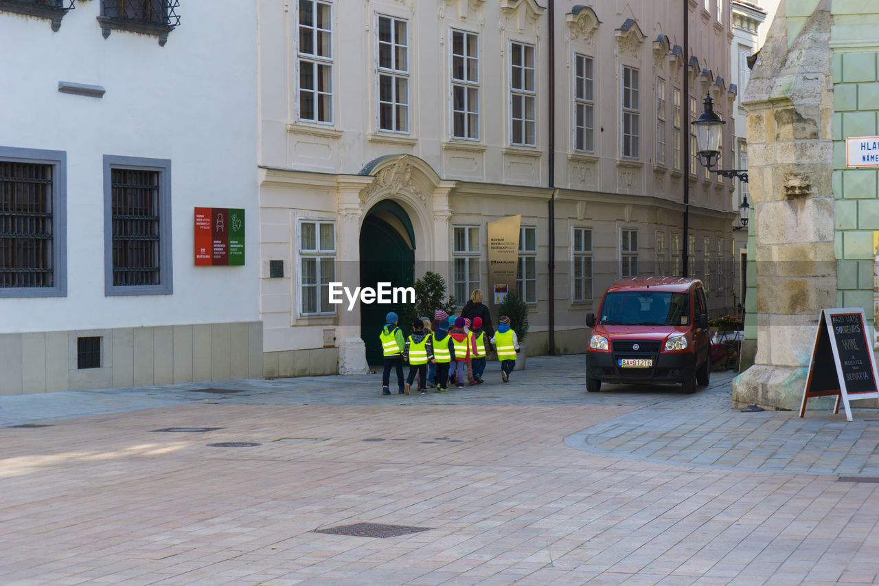 Children walking on street amidst buildings in city