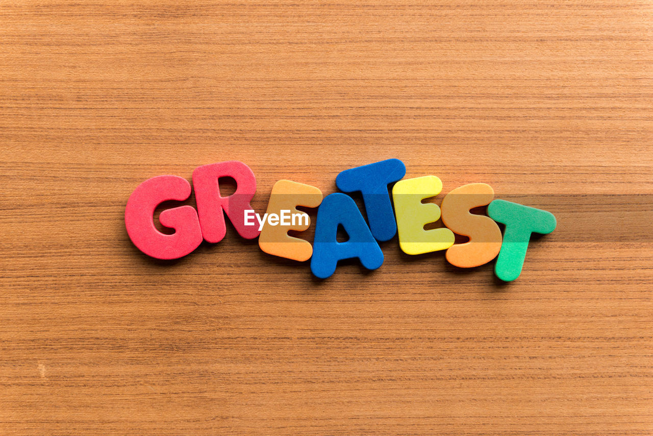 High angle view of colorful greatest text on wooden table