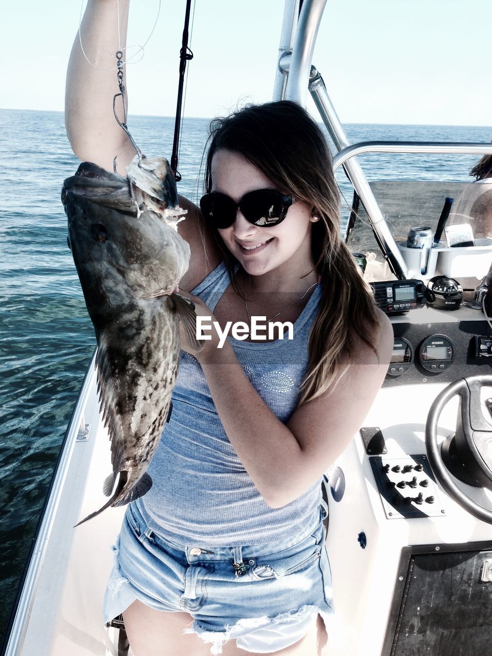 YOUNG WOMAN WEARING SUNGLASSES AT SEA