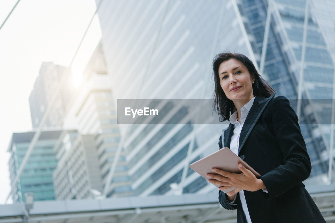 Portrait of businesswoman using digital tablet while standing outdoors