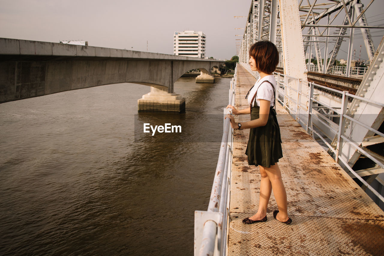 Side view of woman standing on bridge