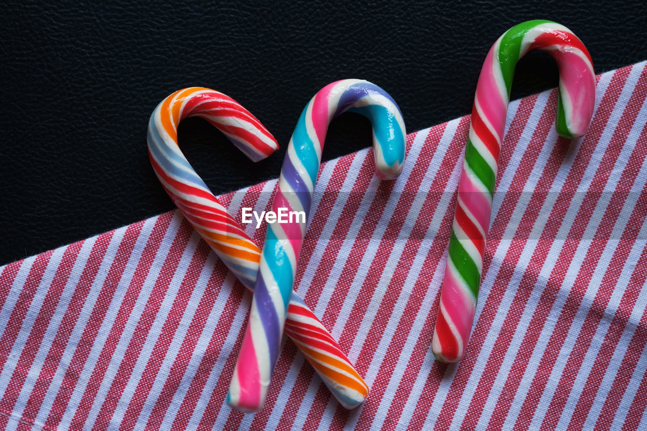 High angle view of fresh colorful candy canes on striped napkin against black background