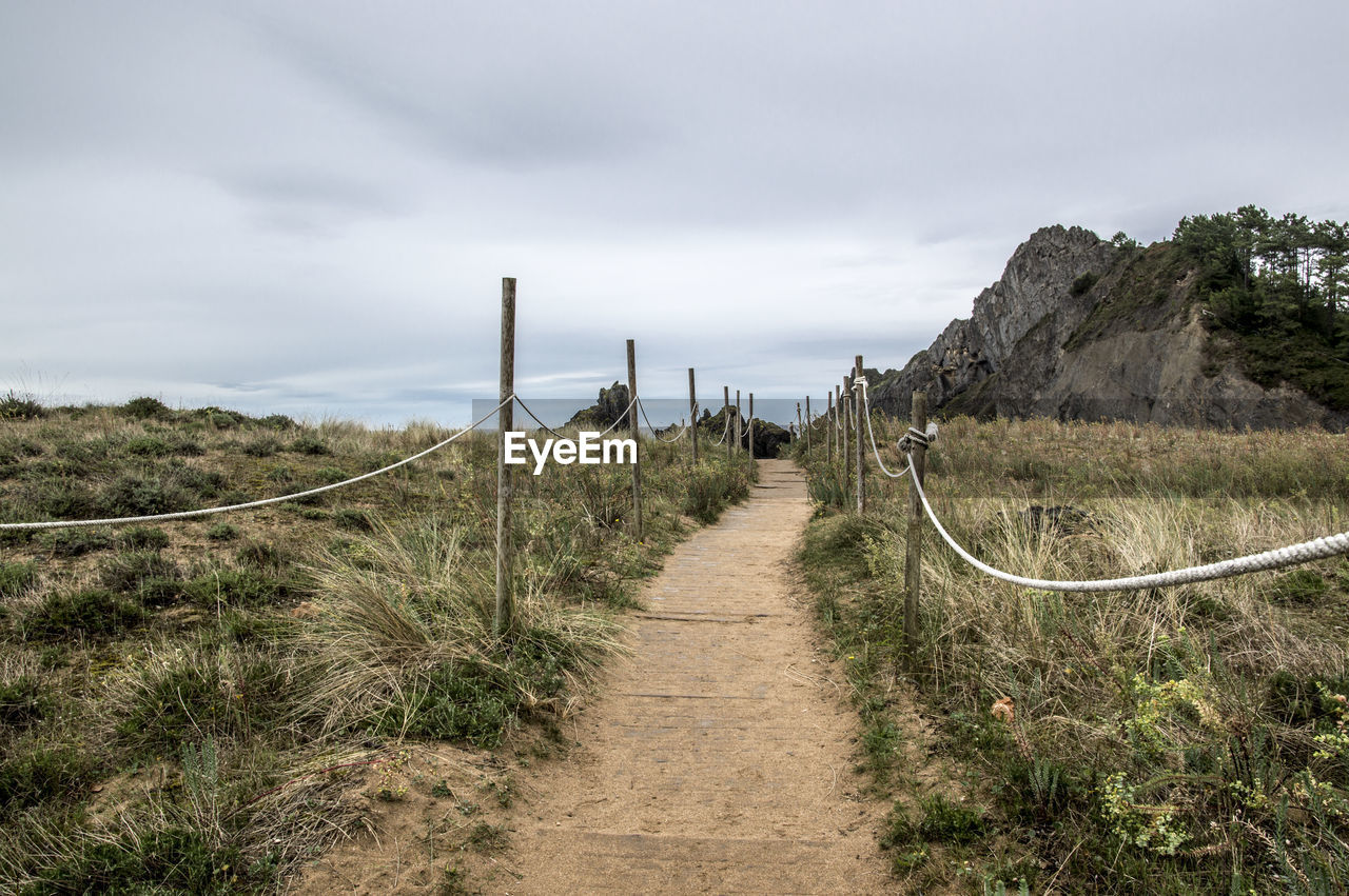 Walkway leading towards mountain against sky