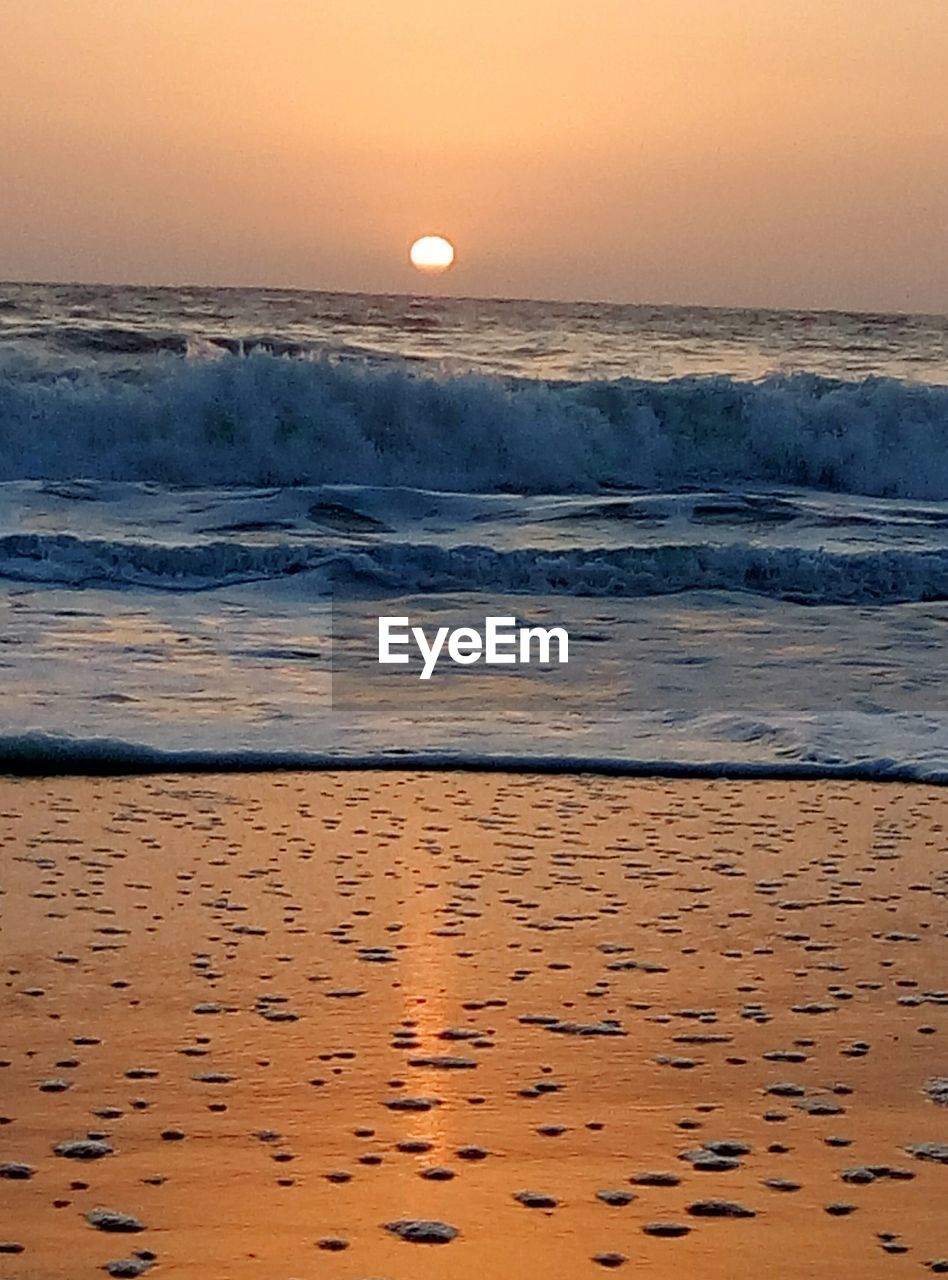 SCENIC VIEW OF BEACH AGAINST SKY AT SUNSET