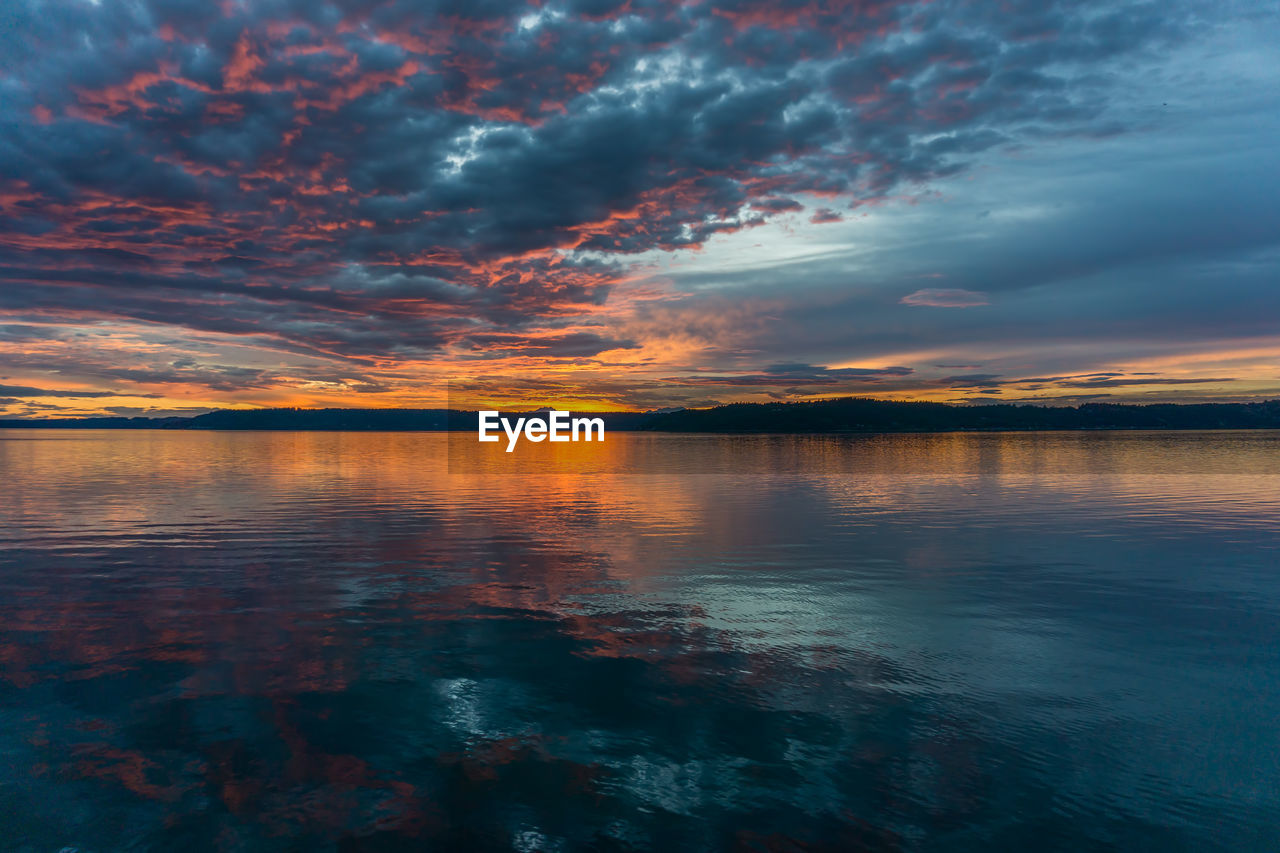 Scenic view of sea against dramatic sky during sunset