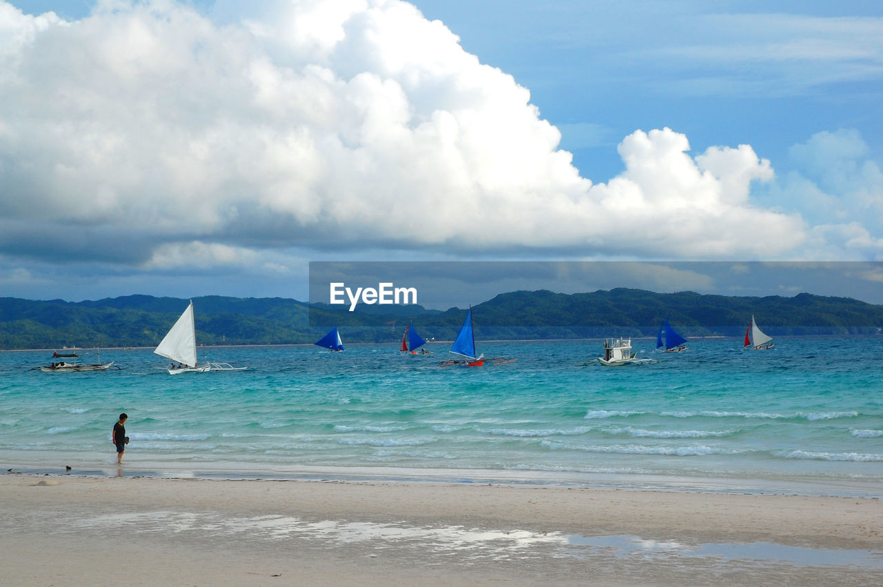 PEOPLE ON BEACH BY SEA AGAINST SKY