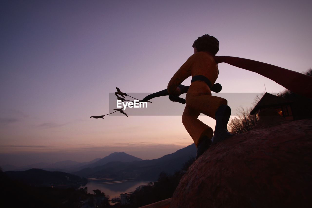 MAN STANDING ON MOUNTAIN DURING SUNSET