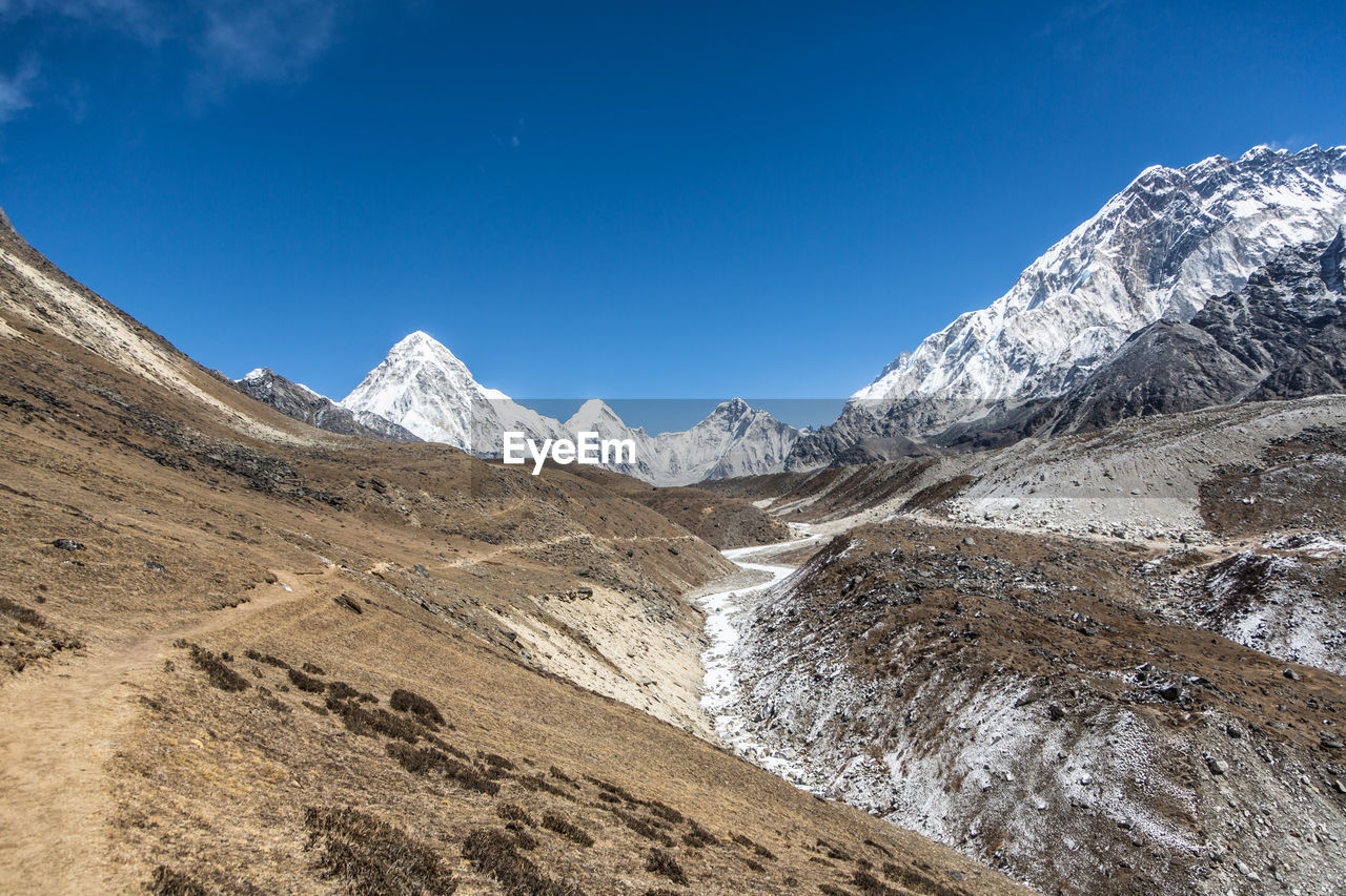 Scenic view of snowcapped mountains against blue sky