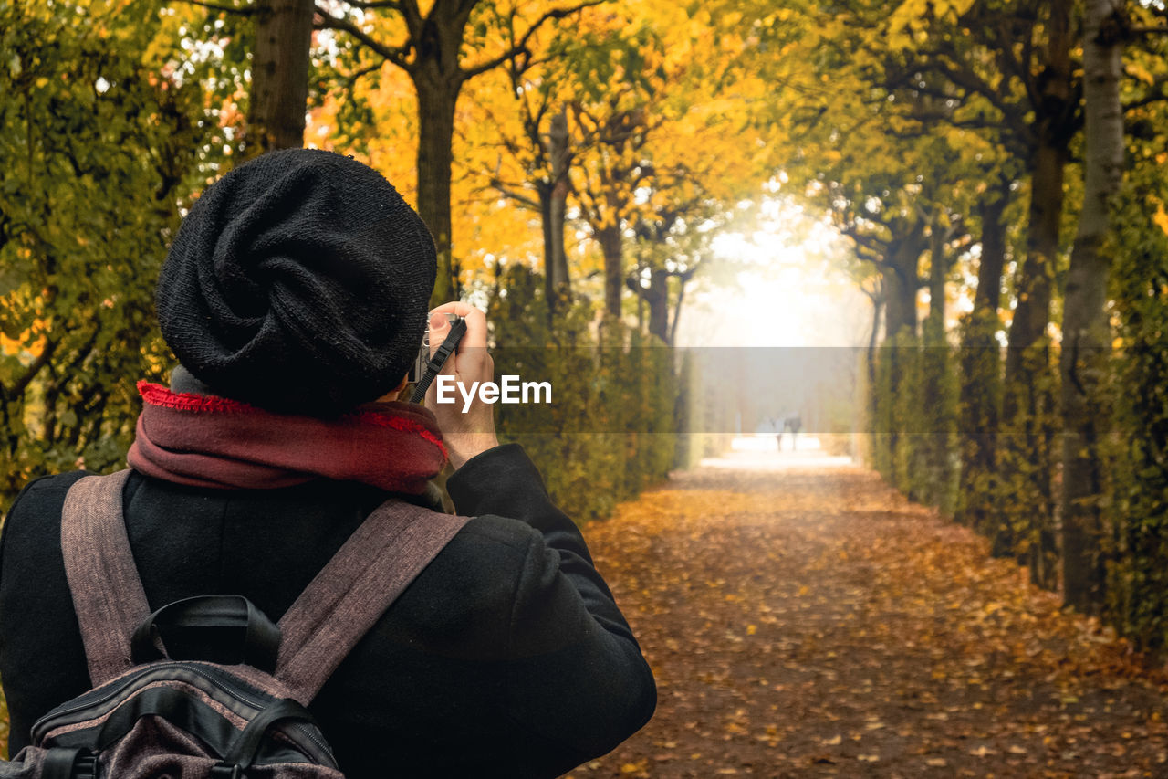 REAR VIEW OF WOMAN WALKING IN PARK DURING AUTUMN