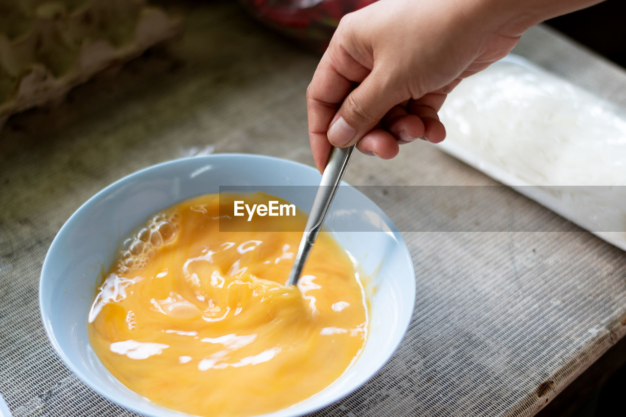 Hand holding the egg beating spoon to prepare fried eggs