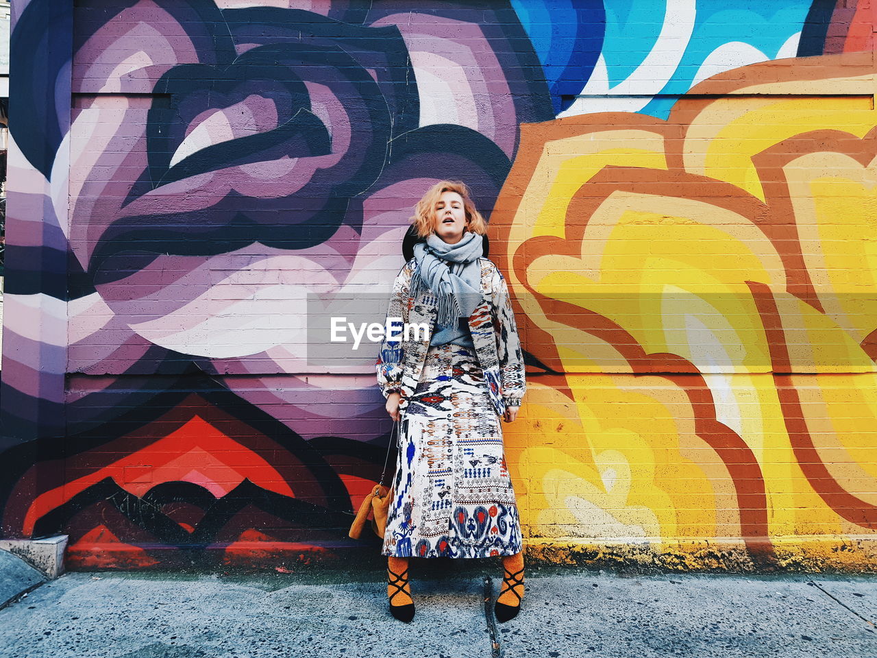 FULL LENGTH OF WOMAN STANDING AGAINST WALL