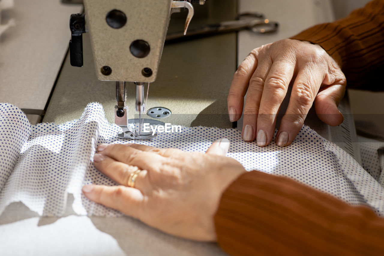 Close up of senior dressmaker hands using a sewing machine.