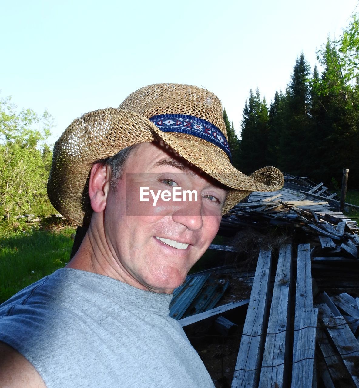 Portrait of man wearing hat against trees and sky