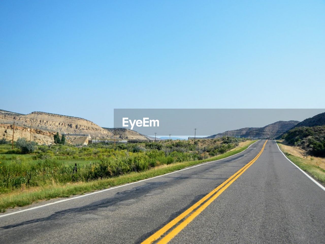 Road passing through landscape against clear sky