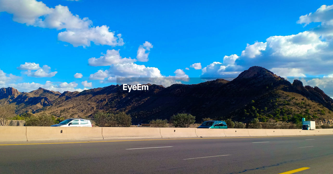 Highway by mountains against blue sky