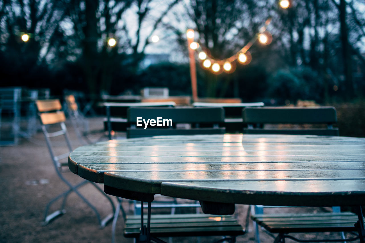 Empty chairs and tables at outdoor restaurant during dusk