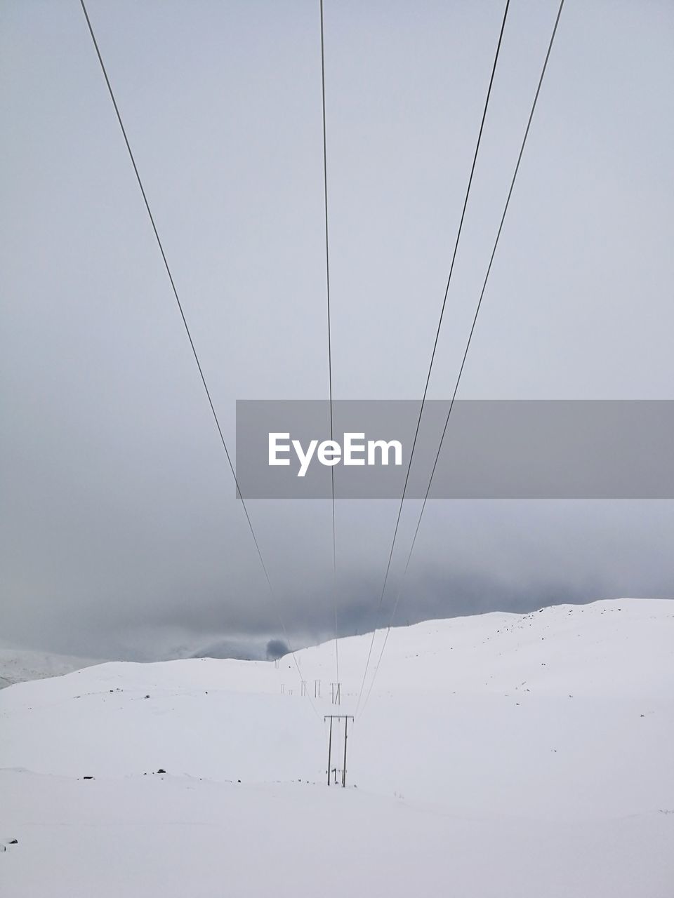 Ski lift over snow covered mountains against sky