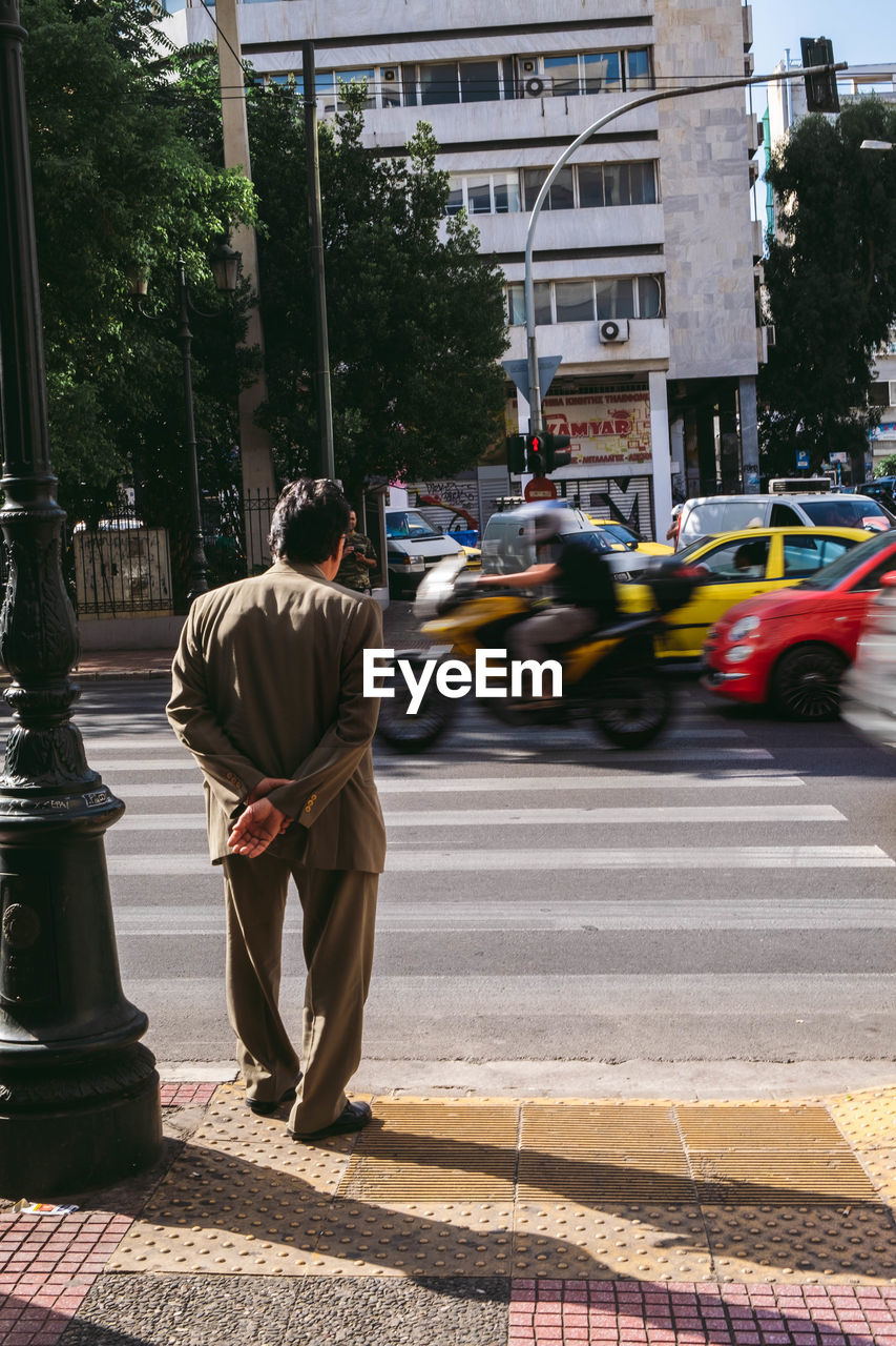 REAR VIEW OF MAN WALKING ON STREET