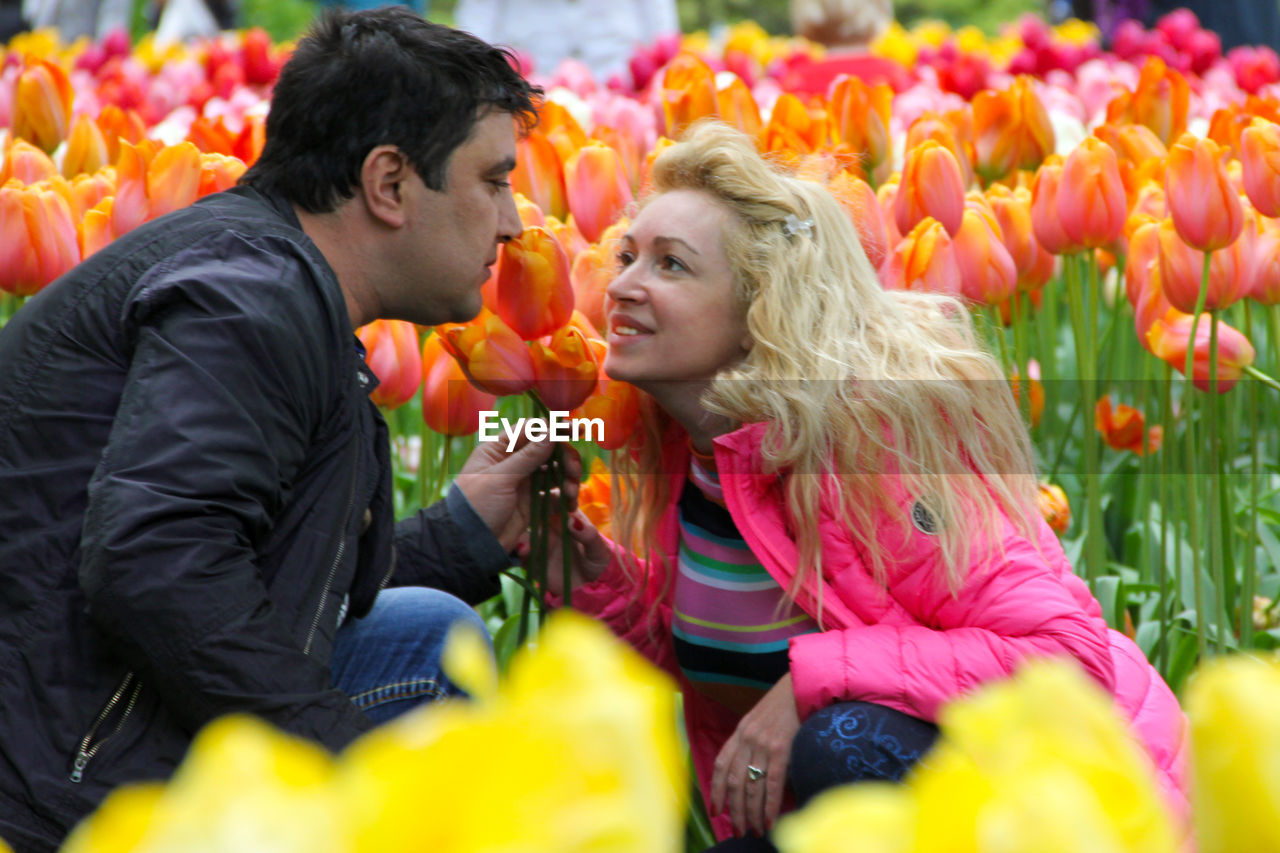 Couples sitting amidst tulip field at park