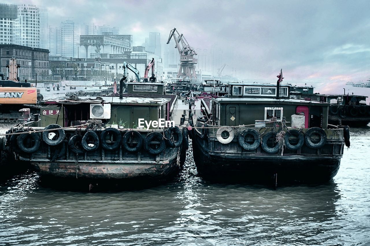 Boats moored on lake against cloudy sky