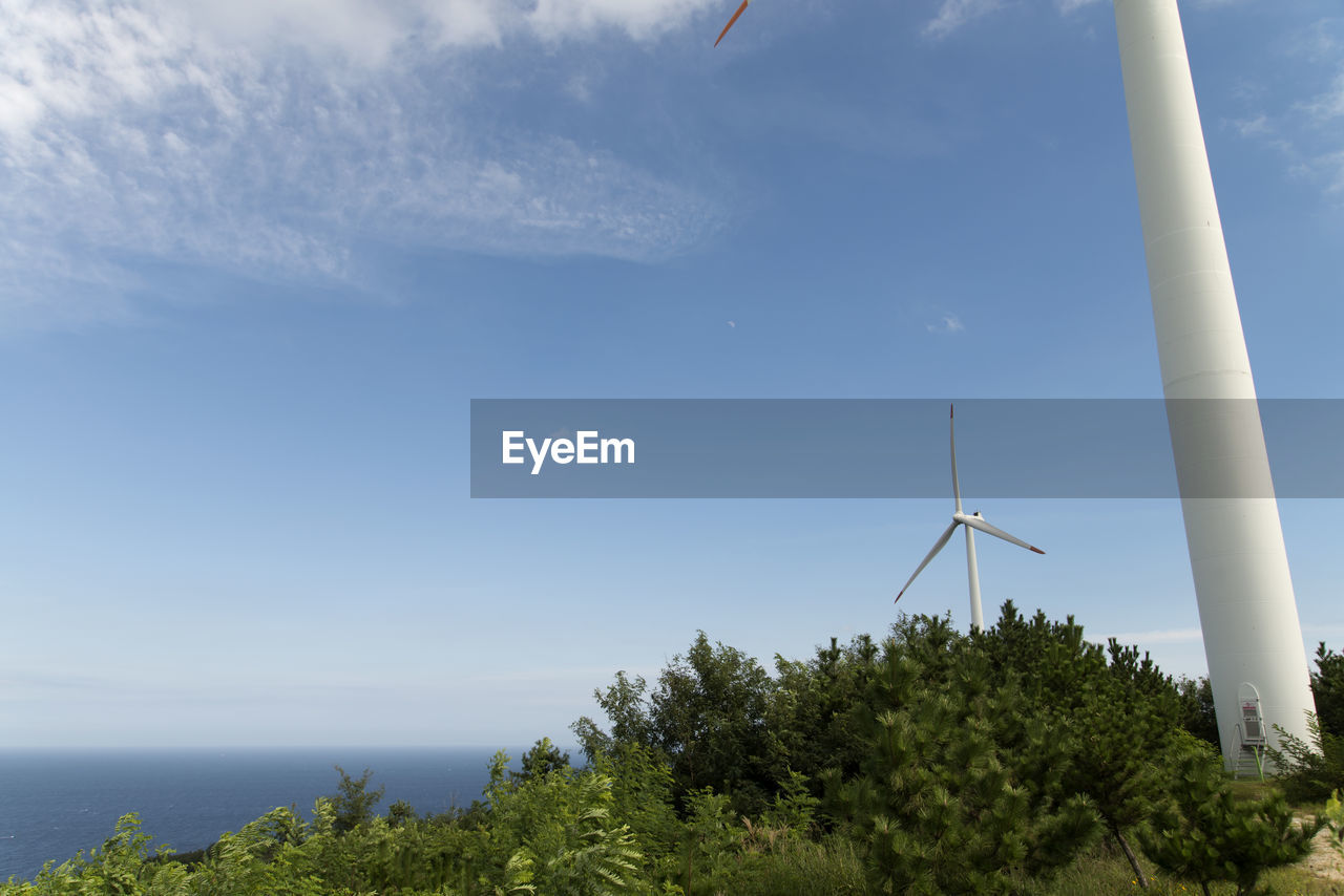 Low angle view of wind turbines against sky