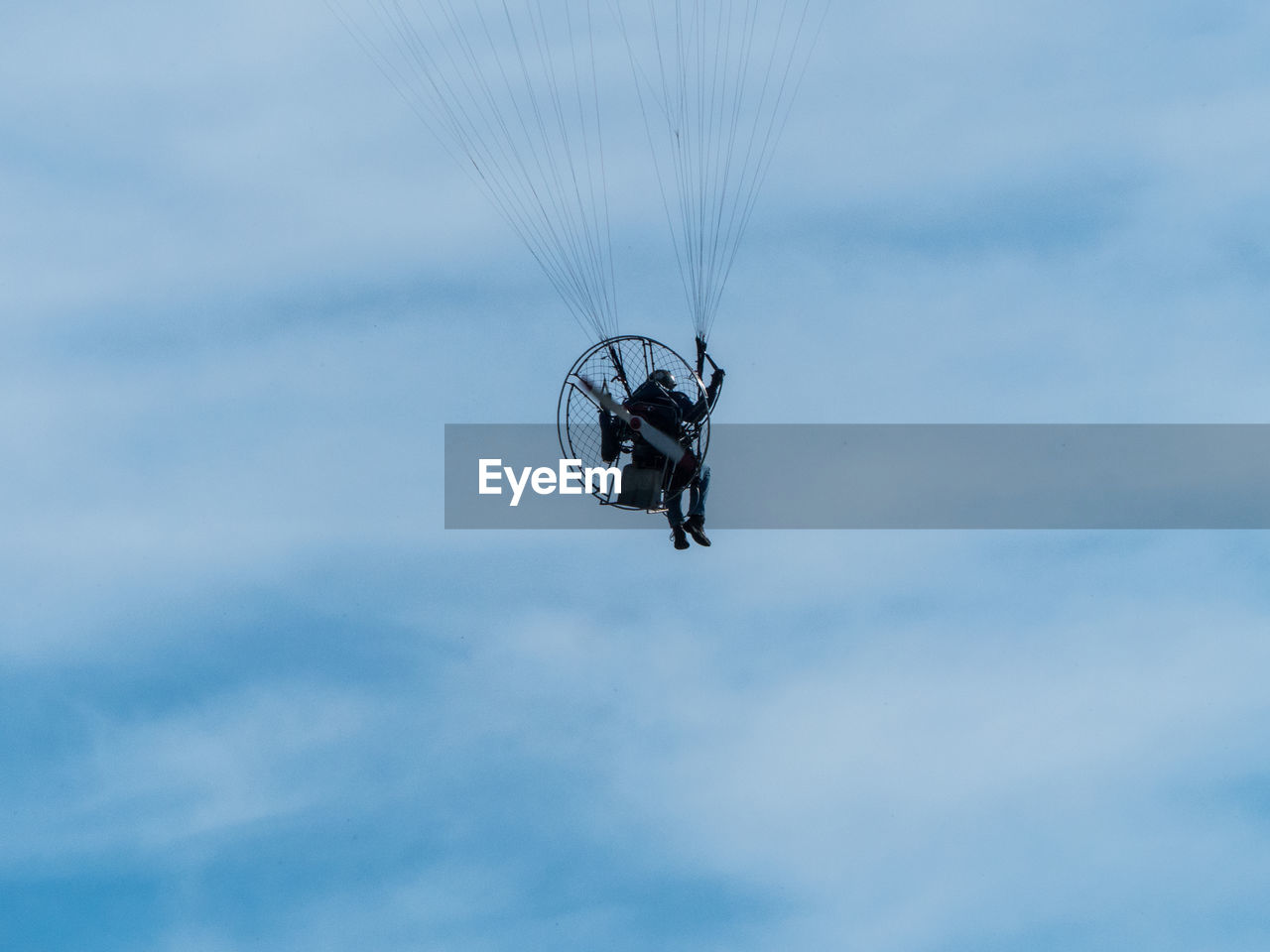 Low angle view of man paragliding against sky