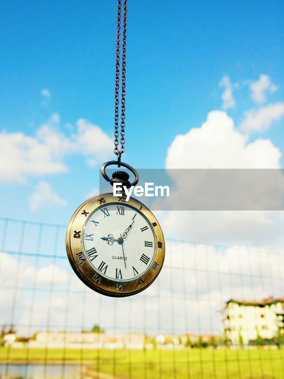 Close-up of antique pocket watch against sky