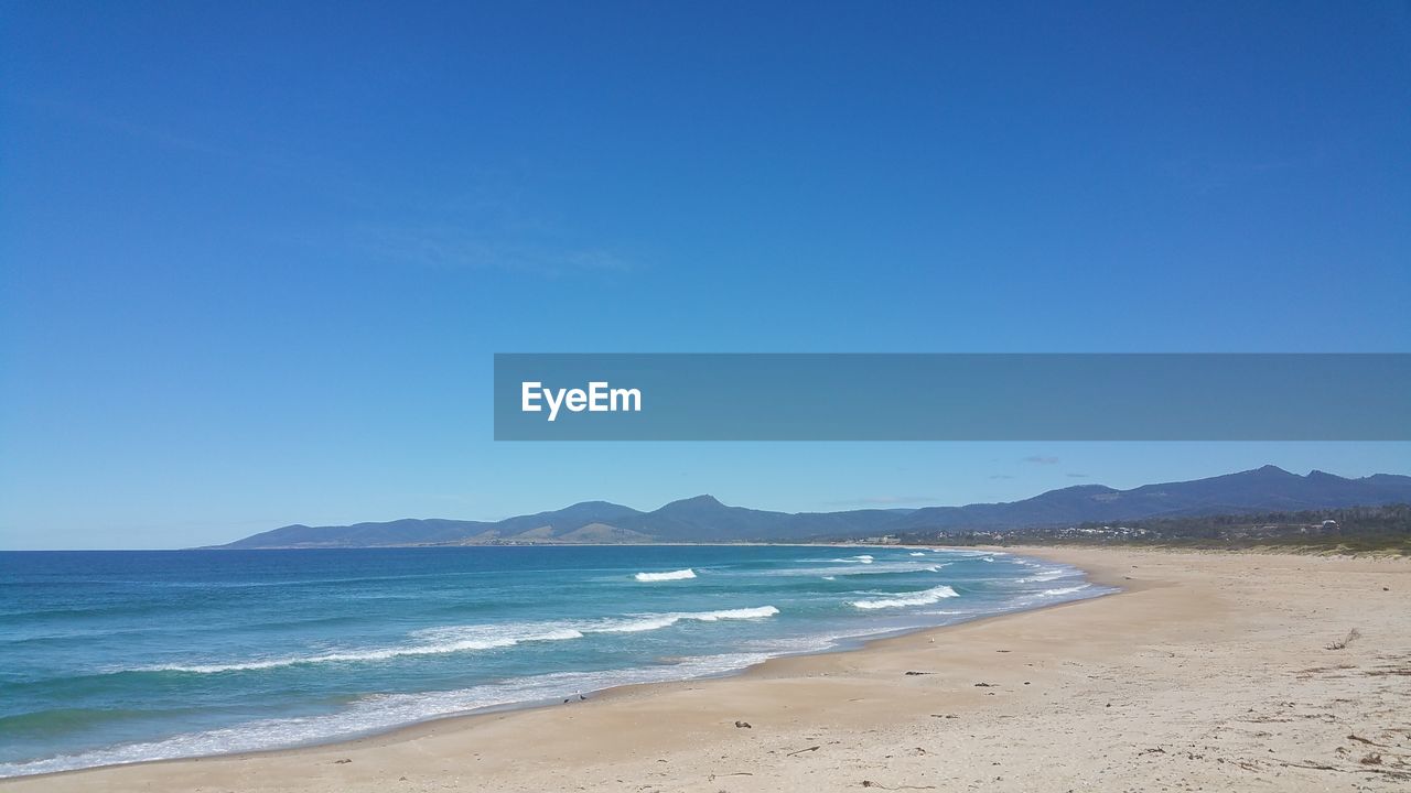 Scenic view of beach against blue sky