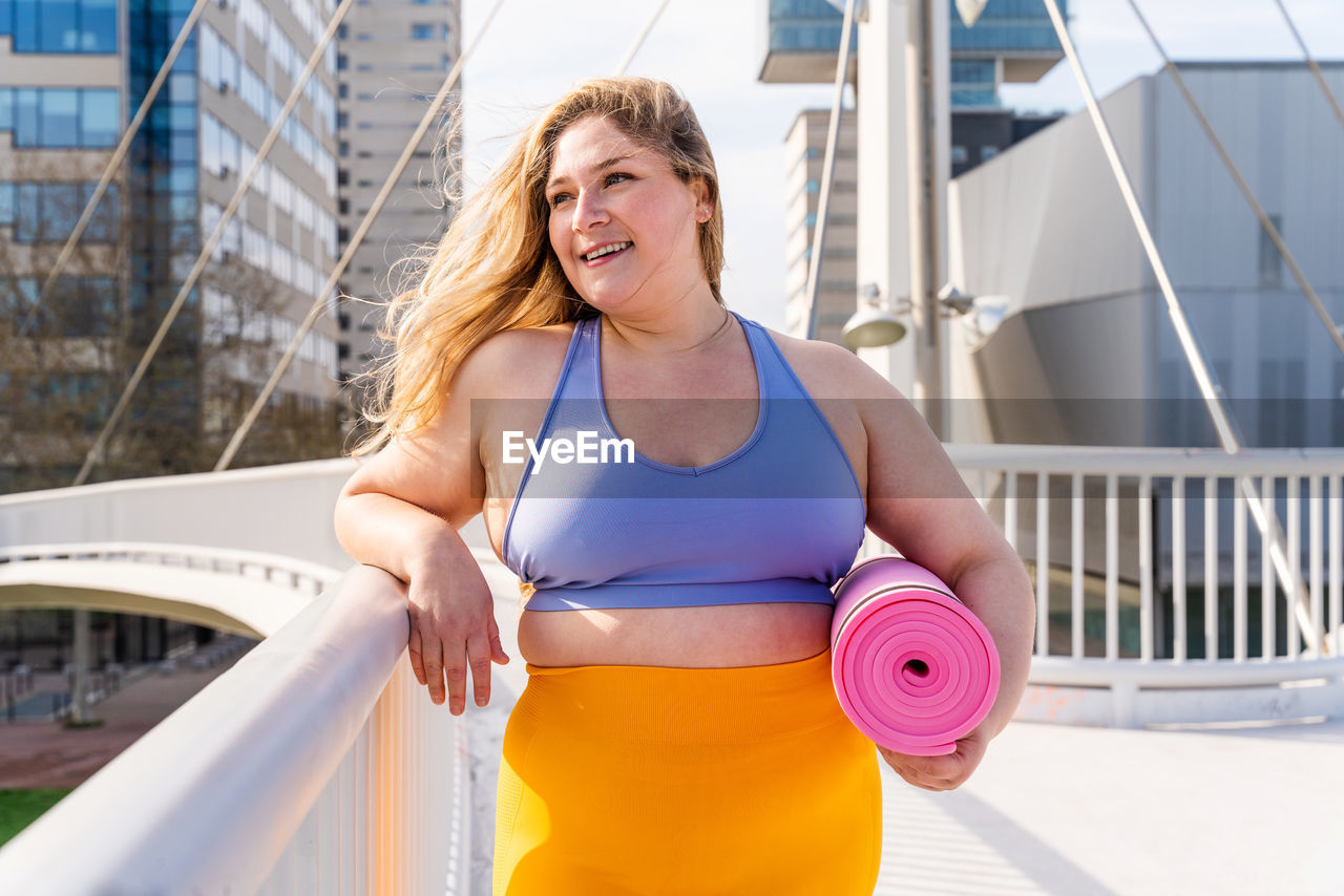 Young woman standing with yoga mat