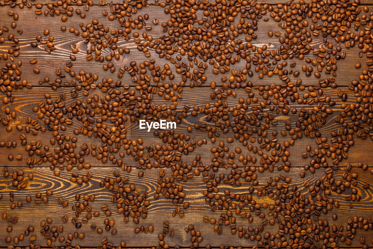 Roasted coffe beans spreaded over wooden board - full frame background, high angle view