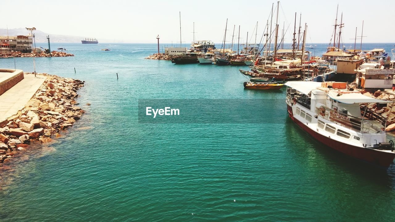 Boats moored at harbor against sky