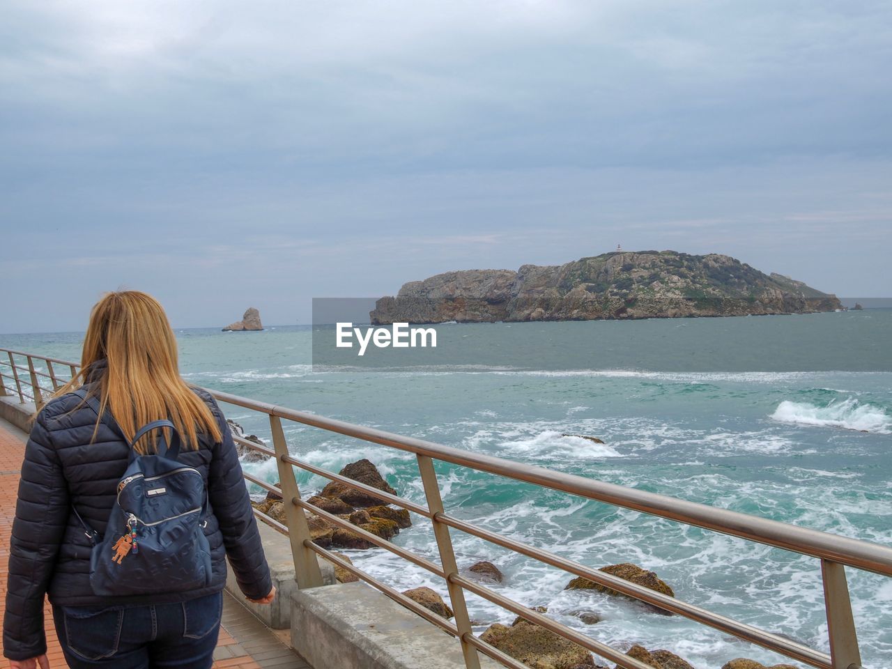 REAR VIEW OF WOMAN LOOKING AT SEA