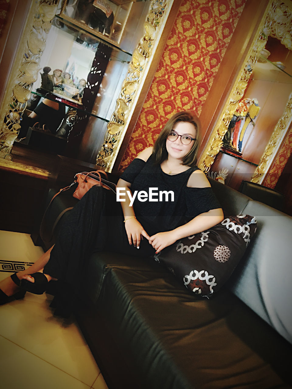 FULL LENGTH PORTRAIT OF WOMAN SITTING ON SOFA AT HOME