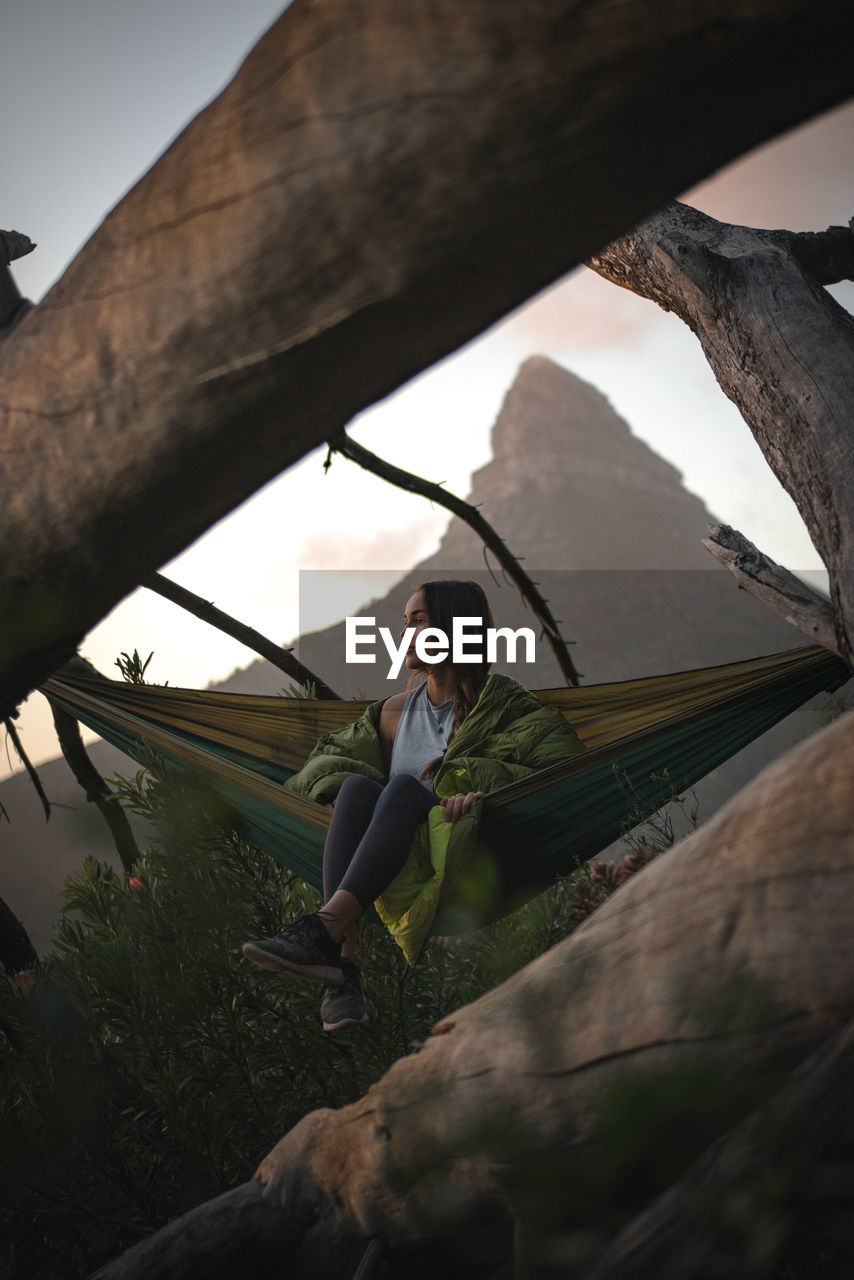 Woman sitting in hammock during sunset