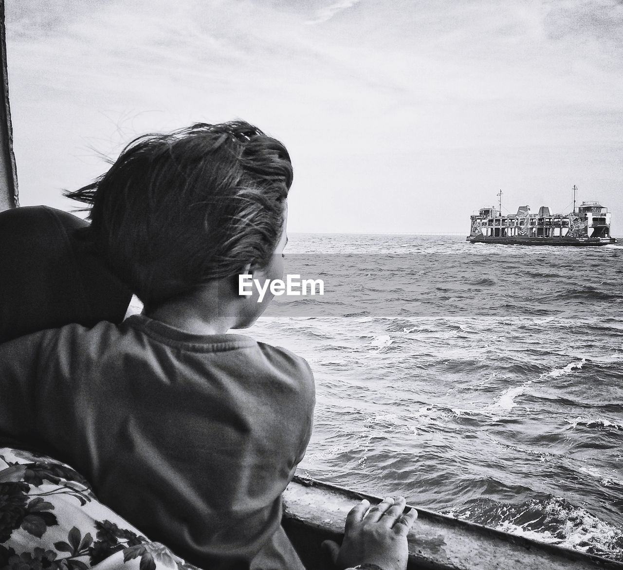 Rear view of boy in boat looking at sea