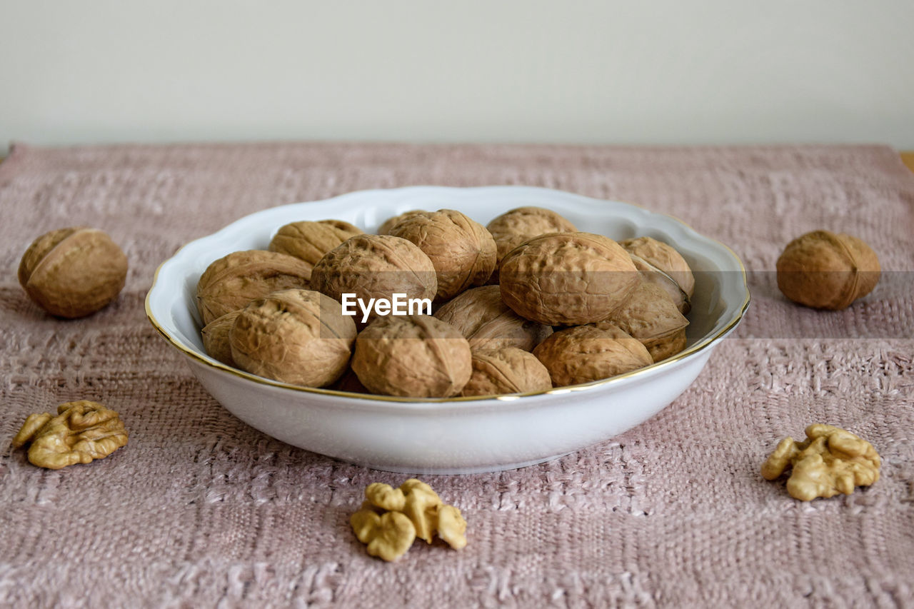 Walnuts in white plate on table covered with beige napkin, close-up
