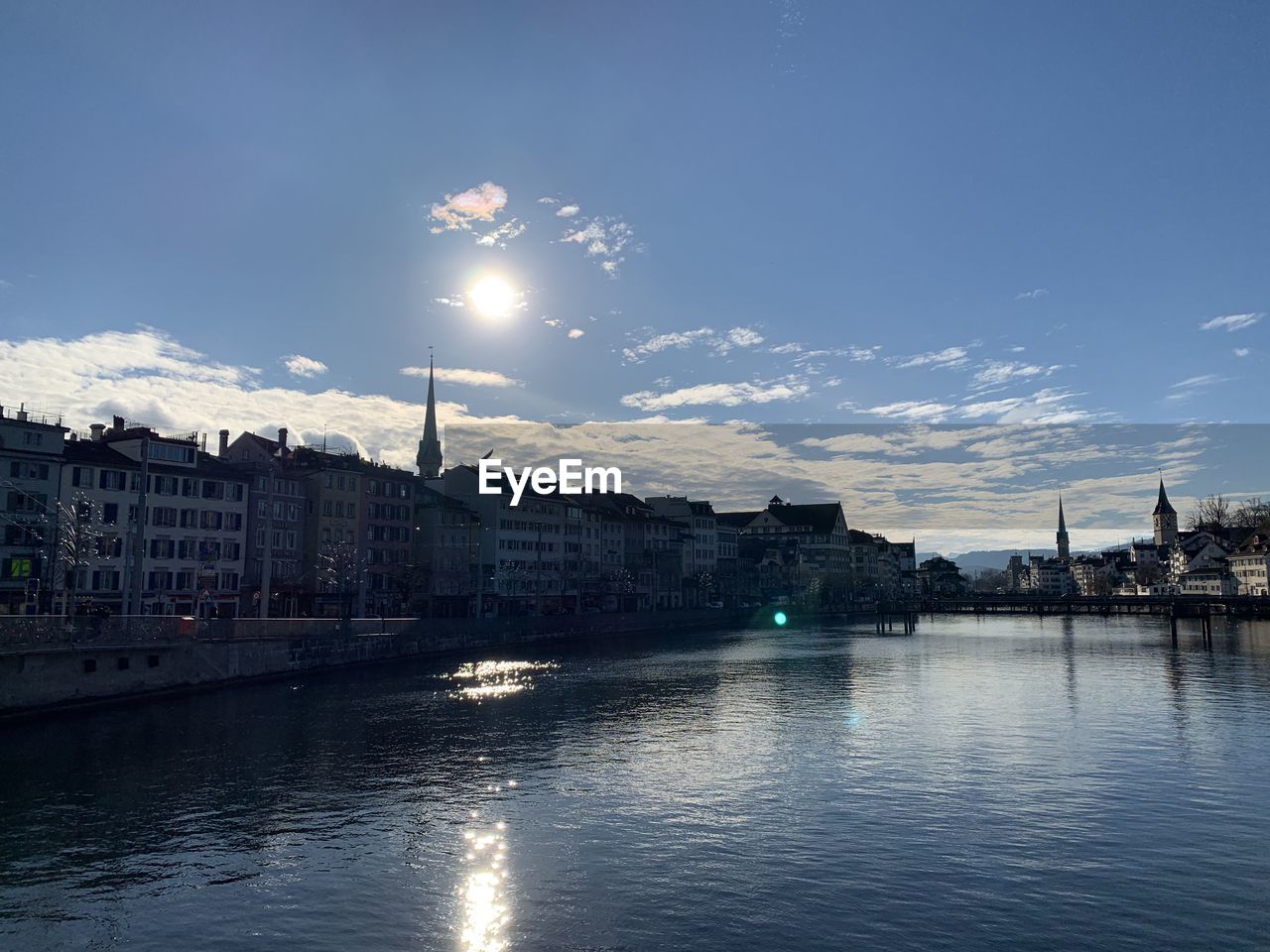 City at waterfront against cloudy sky