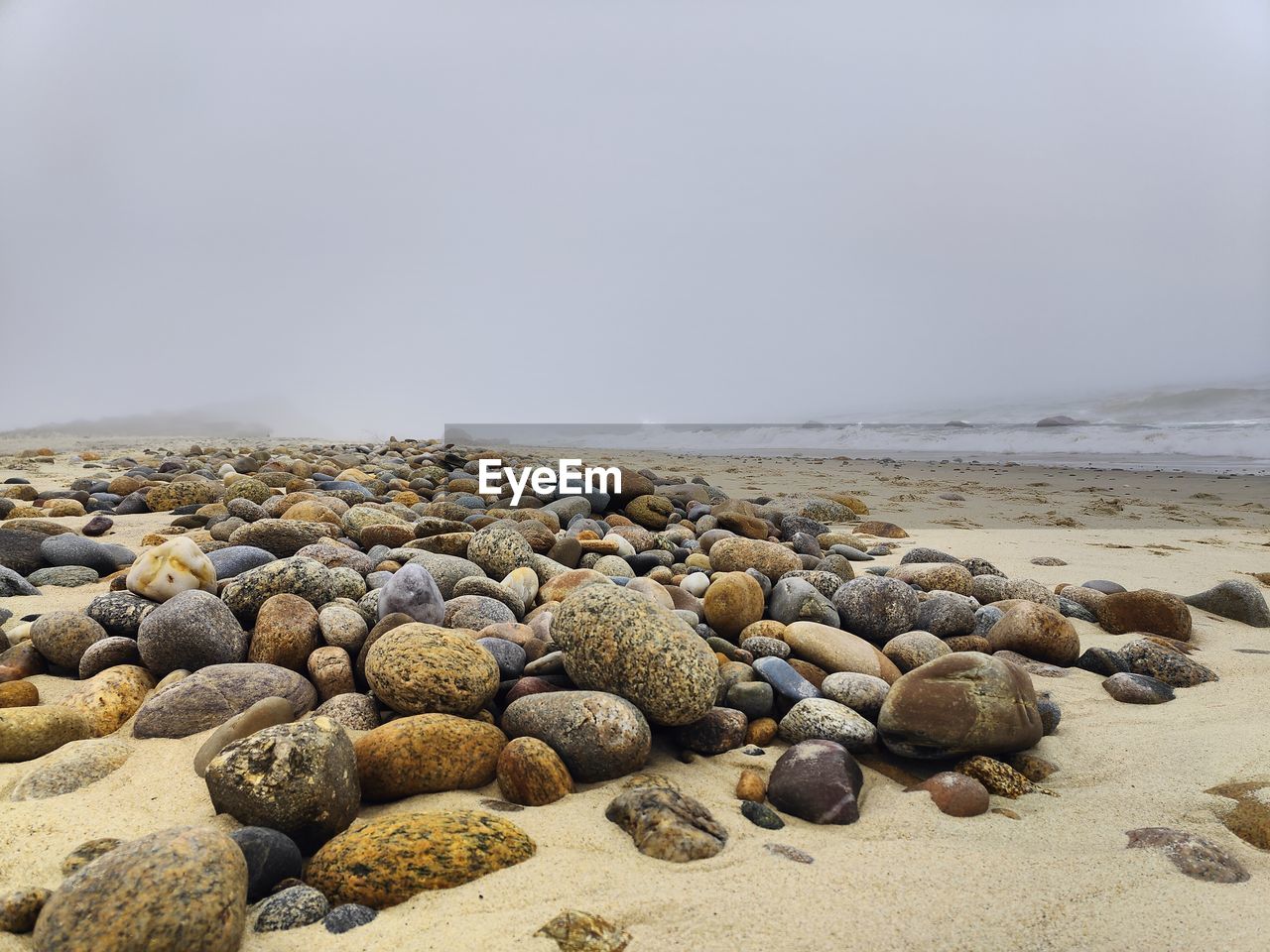 land, beach, sea, sand, rock, shore, water, nature, sky, coast, beauty in nature, tranquility, scenics - nature, pebble, ocean, body of water, tranquil scene, no people, stone, day, environment, outdoors, wave, non-urban scene, water's edge, coastline, horizon over water, cloud, idyllic, travel destinations, horizon, landscape, overcast, copy space, travel