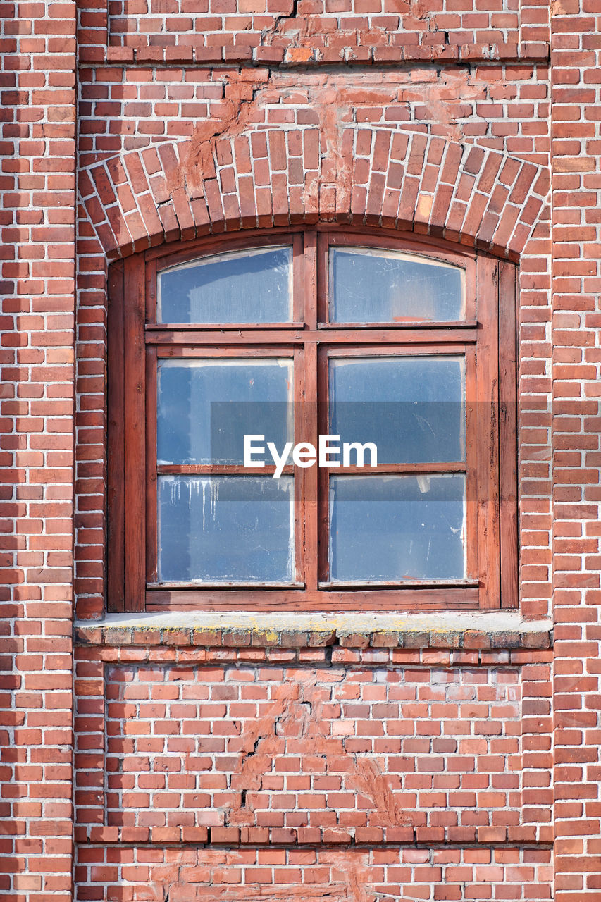 Arched glass window on old red brick wall. vintage window in wooden frame on red brick building wall