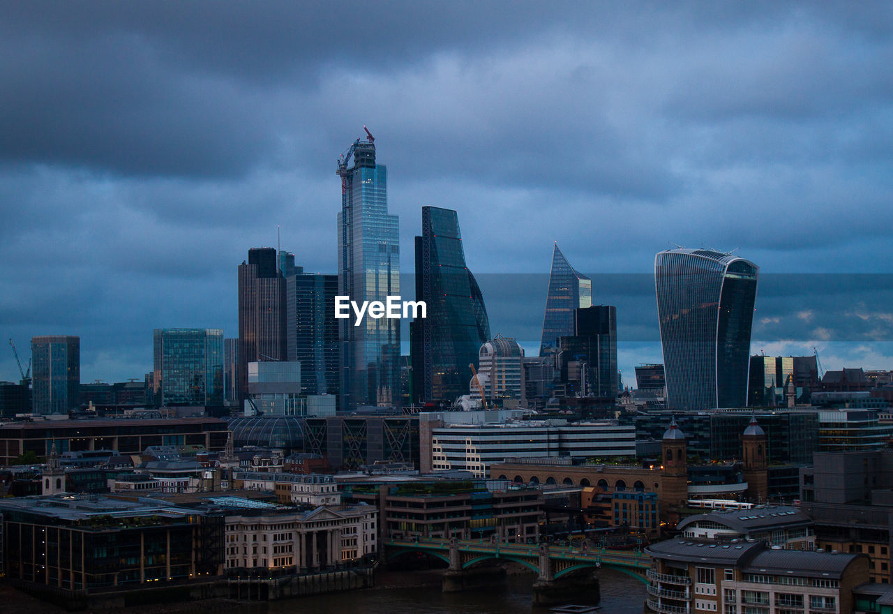 Modern buildings in city against cloudy sky