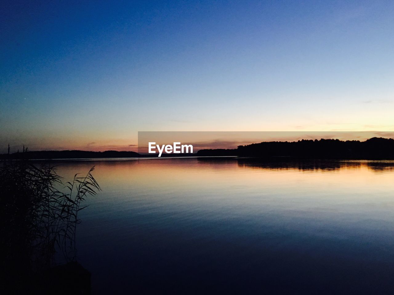 Scenic view of lake against clear sky during sunset