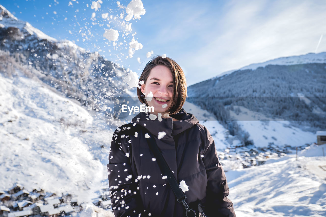 Smiling young woman on snowcapped mountains during winter