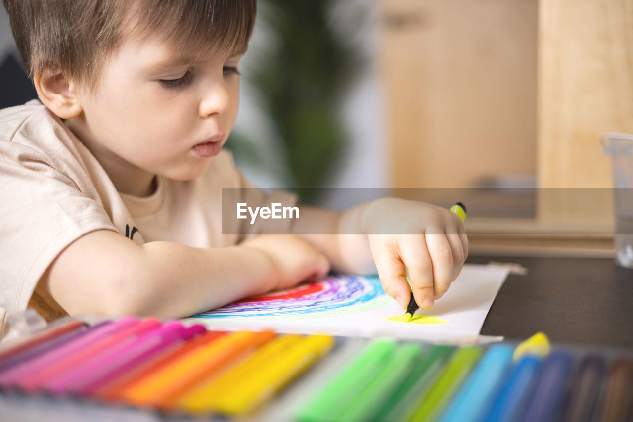 close-up of boy drawing on book at home