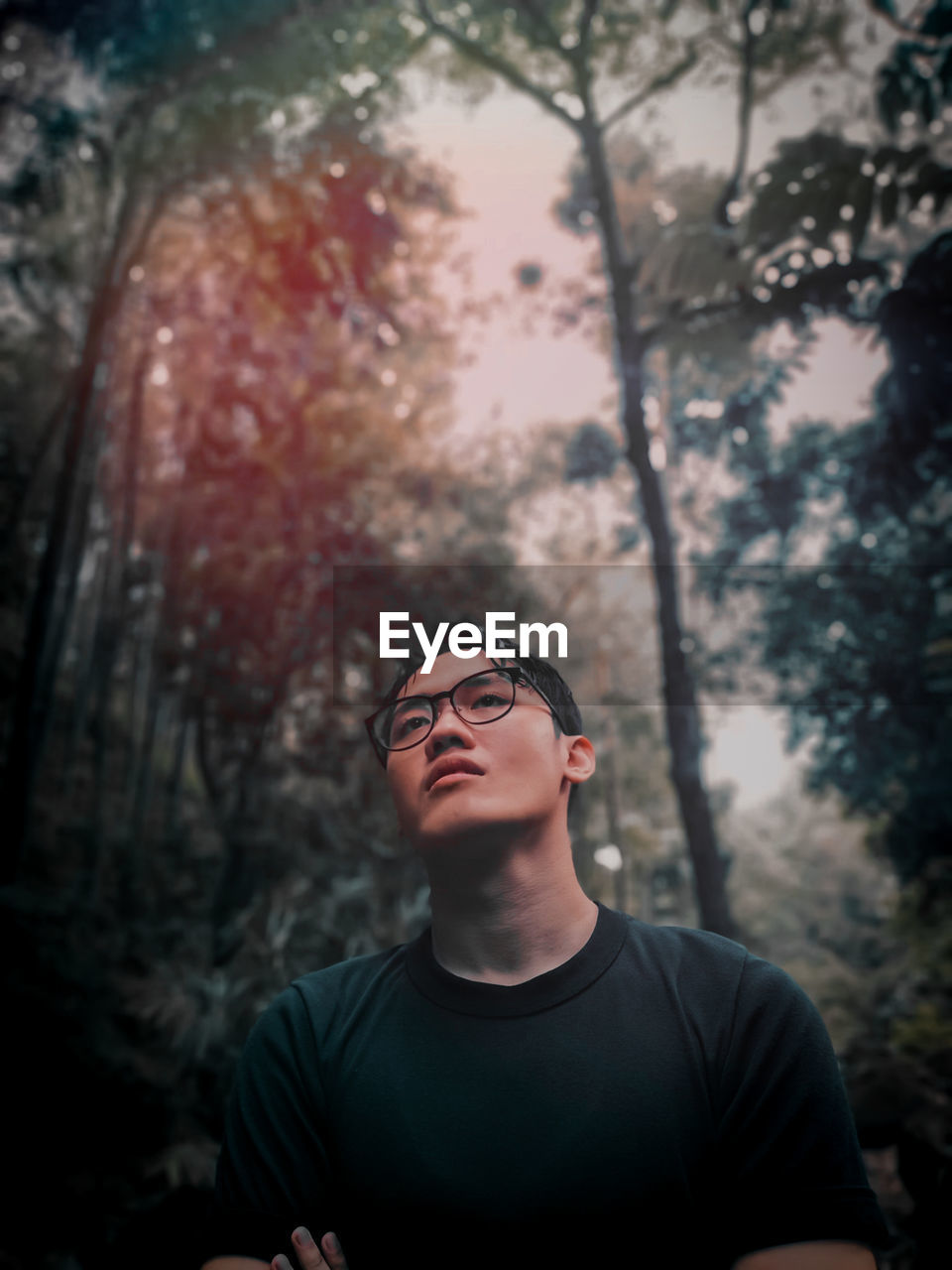 Portrait of young man standing against trees