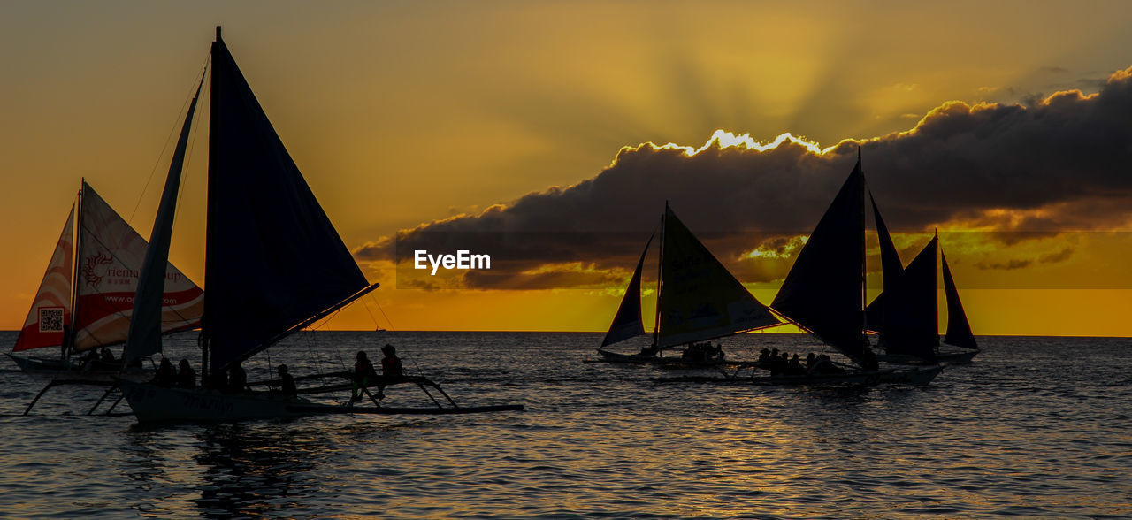 SILHOUETTE MEN ON BOAT IN SEA AGAINST SKY DURING SUNSET