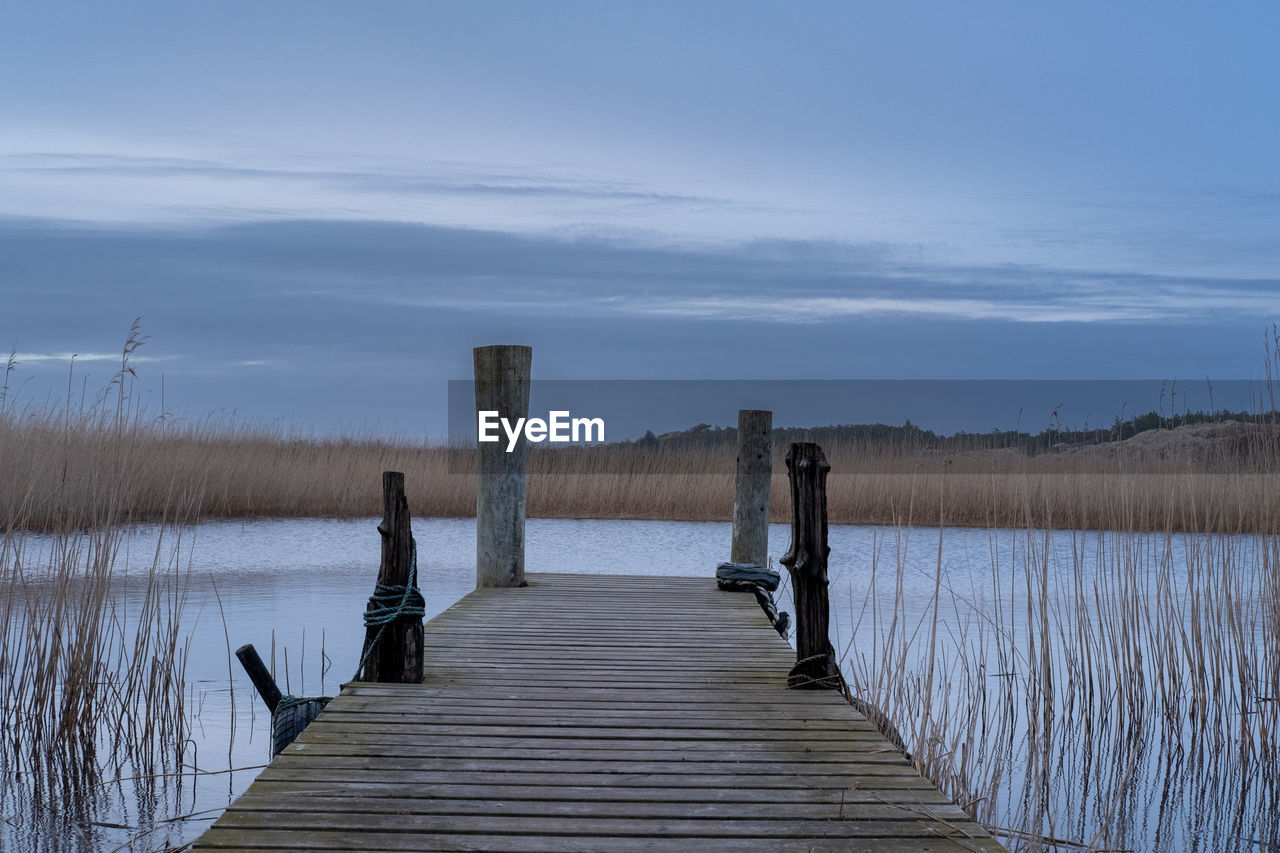 water, wood, sky, reflection, pier, shore, nature, winter, lake, tranquility, scenics - nature, beauty in nature, landscape, jetty, tranquil scene, morning, environment, boardwalk, beach, land, horizon, post, cloud, natural environment, no people, architecture, wooden post, non-urban scene, footpath, plant, the way forward, outdoors, walkway, dock, wetland, travel destinations, day, built structure, reservoir, rural scene, idyllic, travel, coast, grass, blue, tourism